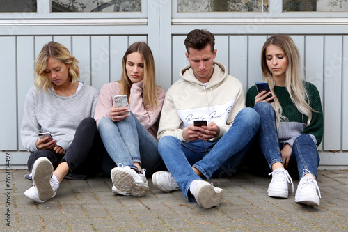 Junge Leute sitzen zusammenn und beschäftigen sich mit ihren Handys