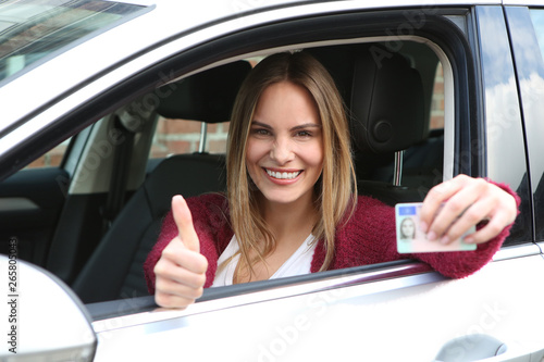 Junge Frau zeigt ihren Führerschein nach bestandener Fahrprüfung