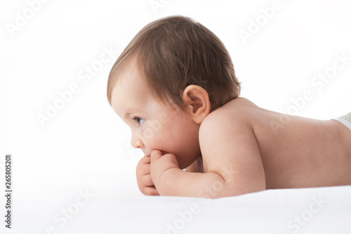 Portrait of adorable baby girl lying naked on her stomach on soft blanket
