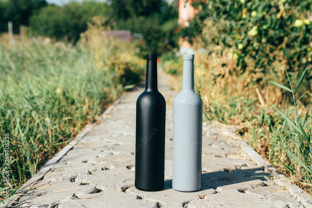 two bottles stand on a rural road, private vineyards. natural drink. wine