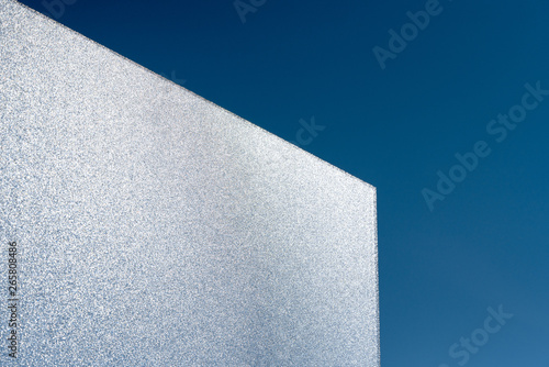 bright light intransparent glass pane reflects shimmering sunlight with clear blue sky behind