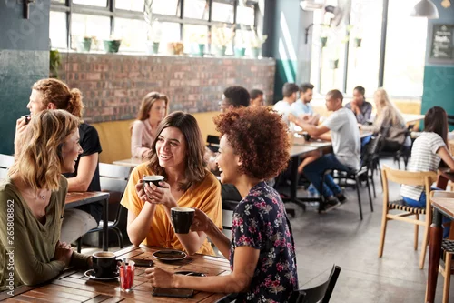 Obraz Trzy młode koleżanki spotkanie siedzieć przy stole w kawiarni i rozmawiać