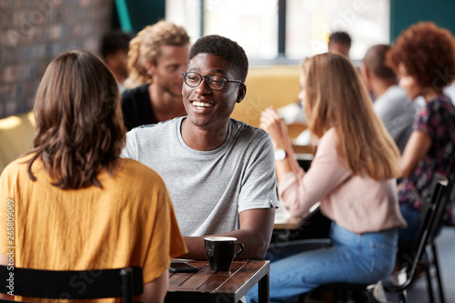 Couple Sitting At Table In Busy Coffee Shop Talking