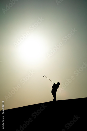 golfista a contraluz golpeando una bola de golf ó golfista al atardecer o silueta de golfista al atardecer 