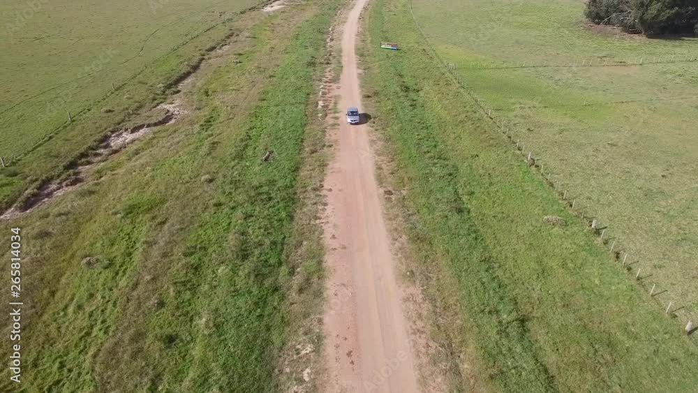 Flying above silver car driving along empty countryside road. People traveling, road trip through beautiful desert scenery in sunny summer Flying above silver car driving along empty countryside road. People traveling, road trip through beautiful desert scenery in sunny summer