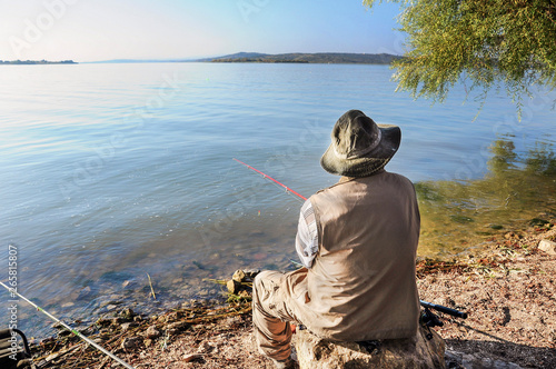 a man fishing by lake in summer photo