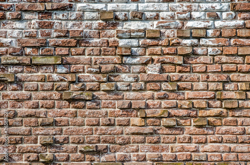 Old masonry wall with chalk and other impurities and with protruding bricks forming an irregular relief pattern
