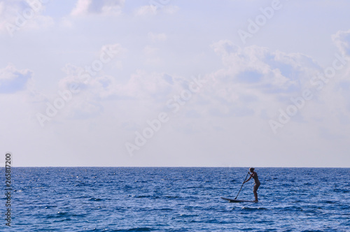Silhouette unidentified girl stand up paddle boarding at the beach - Image holiday/vacation concept © afpejaphotographer
