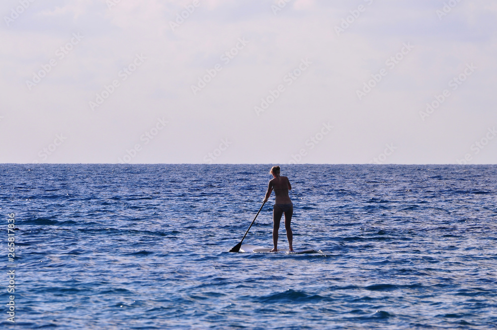 Naklejka premium Silhouette unidentified girl stand up paddle boarding at the beach - Image holiday/vacation concept