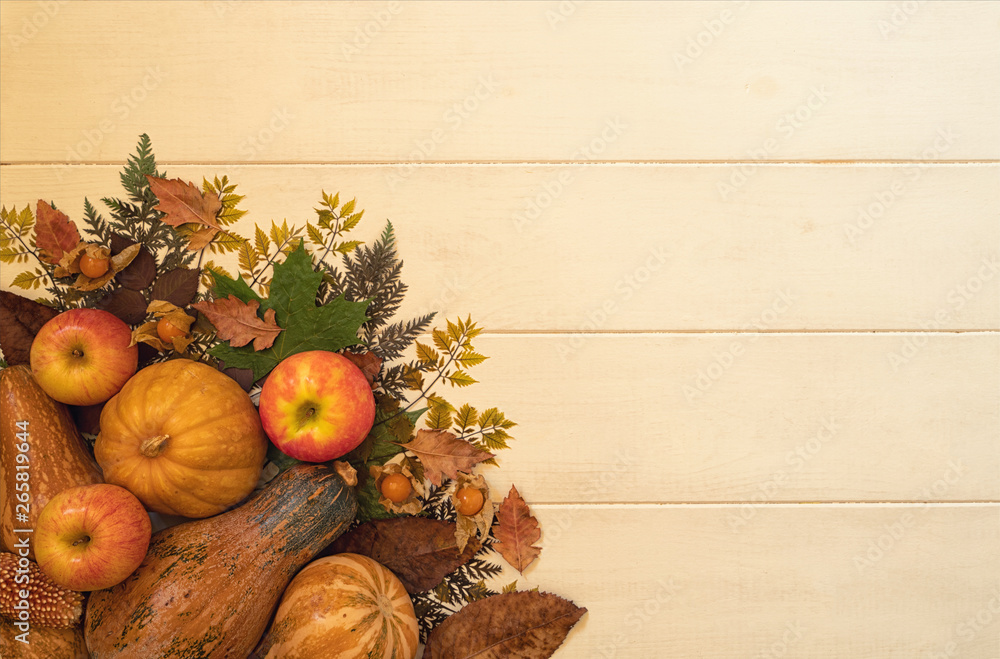 Fresh autumn seasonal vegetables fruits on wooden planks old background. Fallen leaves, red apples, corn, walnuts and pumpkins. Harvest and gardening concept. Healthy food. Top view with copy space.