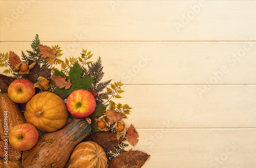 Fresh autumn seasonal vegetables fruits on wooden planks old background. Fallen leaves, red apples, corn, walnuts and pumpkins. Harvest and gardening concept. Healthy food. Top view with copy space.