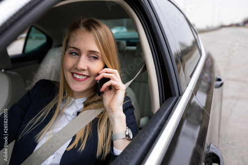 Beautiful young businesswoman is driving her car and talking on the phone