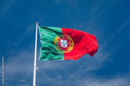 Beautiful large Portuguese flag waving in the wind against blue sky. Portuguese Flag Waving Against Blue Sky. Flag of Portugal waving, against blue sky