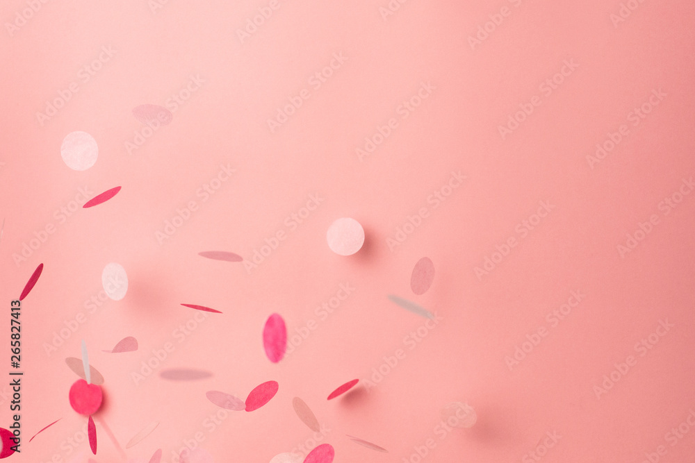 Pink confetti on pink background. Copyspace for text. Bright and festive holiday background.
