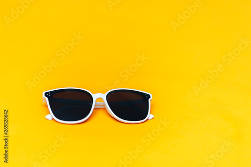 white sunglasses on bright yellow background, copyspace, summer is coming concept