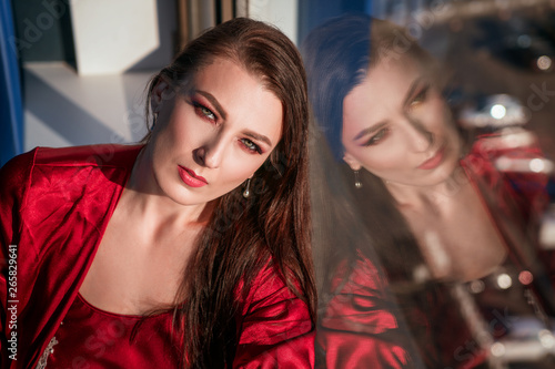 beautiful woman sitting at the window in a red negligee, brooding view