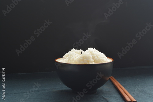 bowl of steamed white rice with chopstick and black background