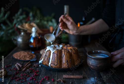 Cooking homemade cake Christmas Eve at home rustic kitchen. Woman's hands make pudding. Ingredients for cooking christmas baking on dark wooden table. Merry Christmas and Happy Holidays! Toned image.