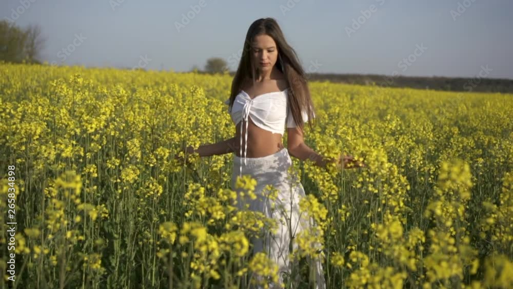 Happy girl walking on the rape field, steadicam shot, slow motion shot Happy girl walking on the rape field, steadicam shot, slow motion shot