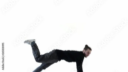 A man dancer jumps out of the bottom in slow motion freezes and falls down. Black clothes on a white background. (ID: 265838495)