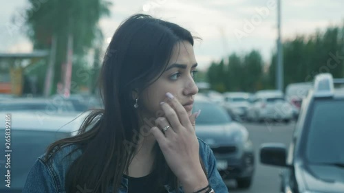 Pensive young woman vaping on the parking near the mall