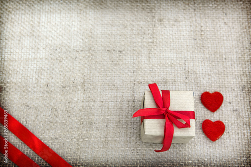 Two hearts and gift isolated on brown cloth background.