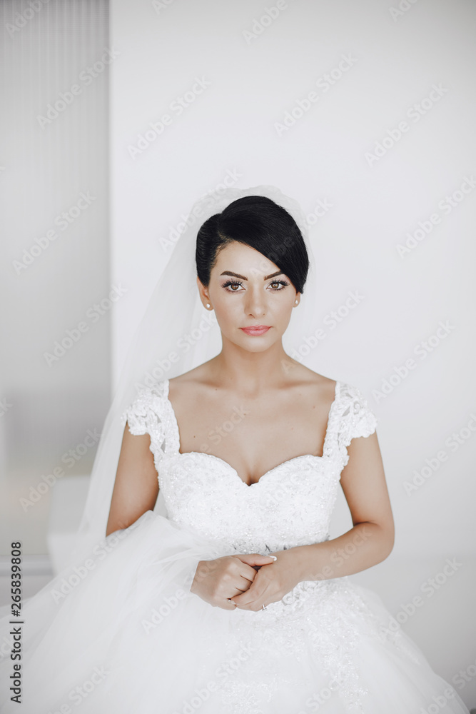 A elegant and beautiful bride at home standing near window A elegant and beautiful bride at home standing near window