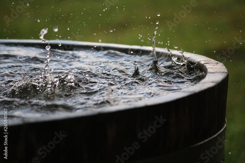 rain is falling in a wooden barrel full of water in the garden