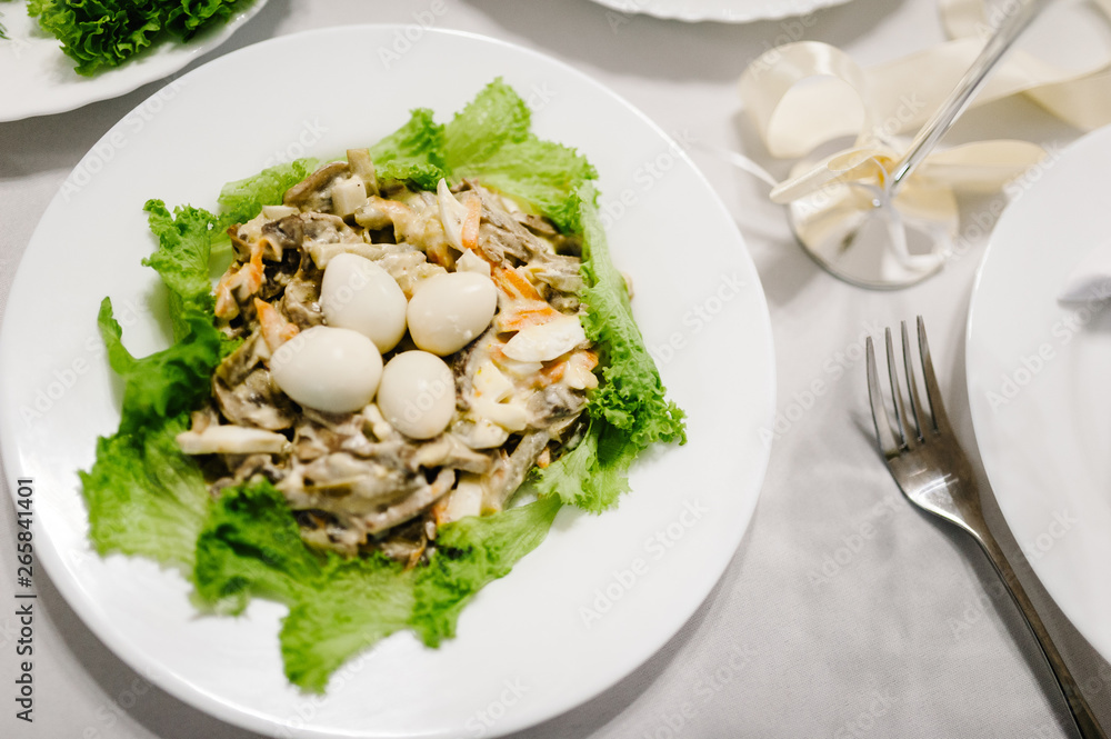 Gourmet salad in a white plate. Slices of cheese, eggs, lettuce. White plate on white table. Food. Holiday. flat lay. top view. Gourmet salad in a white plate. Slices of cheese, eggs, lettuce. White plate on white table. Food. Holiday. flat lay. top view.