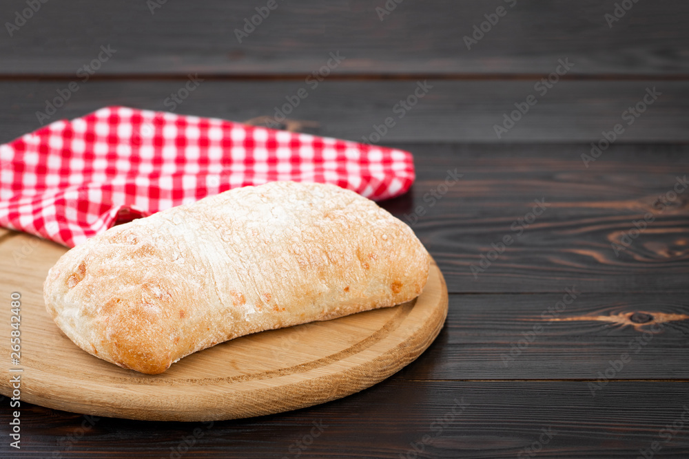 Loaf of ciabatta bread on a cutting board on the dark wooden table
