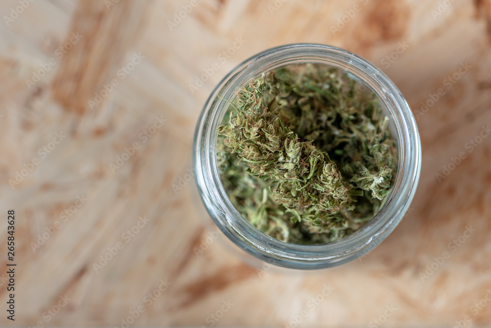 a glass jar filled with marijuana buds, medical hemp with low CBD content a glass jar filled with marijuana buds, medical hemp with low CBD content