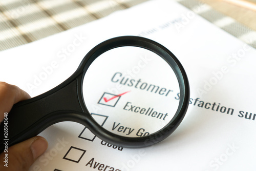 Survey form feedback satisfaction concept: Customer use magnifying glass for checklist excellent over application form document. Opinion question choice fill checkmark for business marketing research