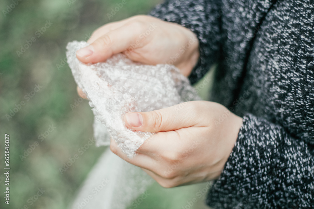 Female hands popping the bubbles in bubble wrap. Selective focus Female hands popping the bubbles in bubble wrap. Selective focus