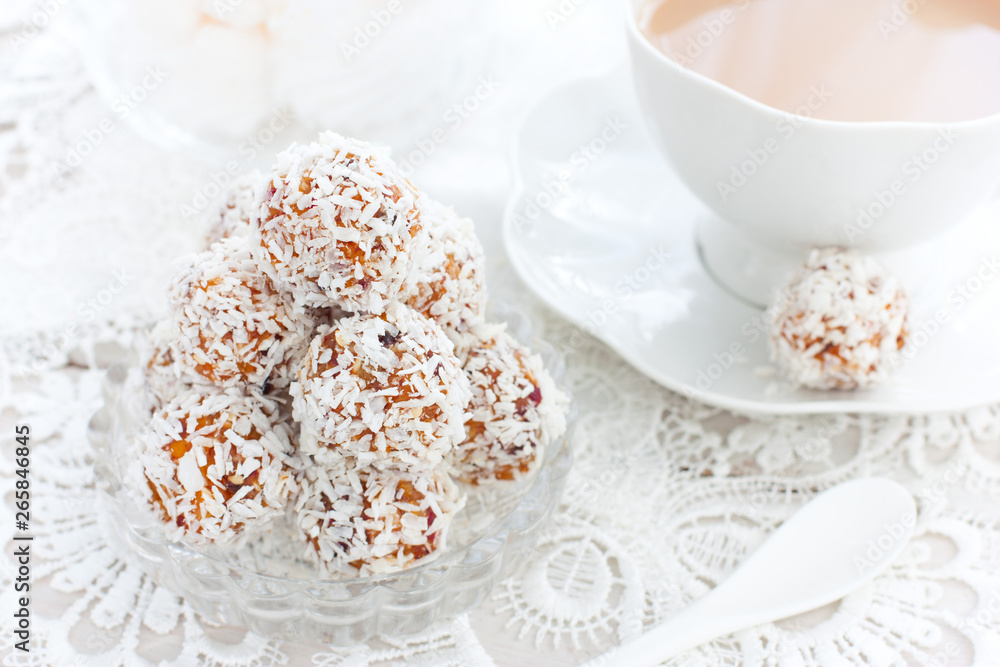 Useful candies of dried fruits in coconut chips in the form of balls on a white table, horizontal, copy space Useful candies of dried fruits in coconut chips in the form of balls on a white table, horizontal, copy space
