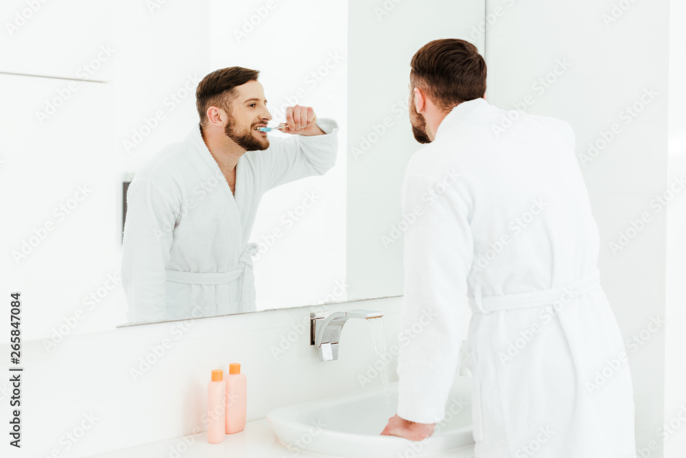 selective focus of handsome bearded man brushing teeth in bathroom selective focus of handsome bearded man brushing teeth in bathroom