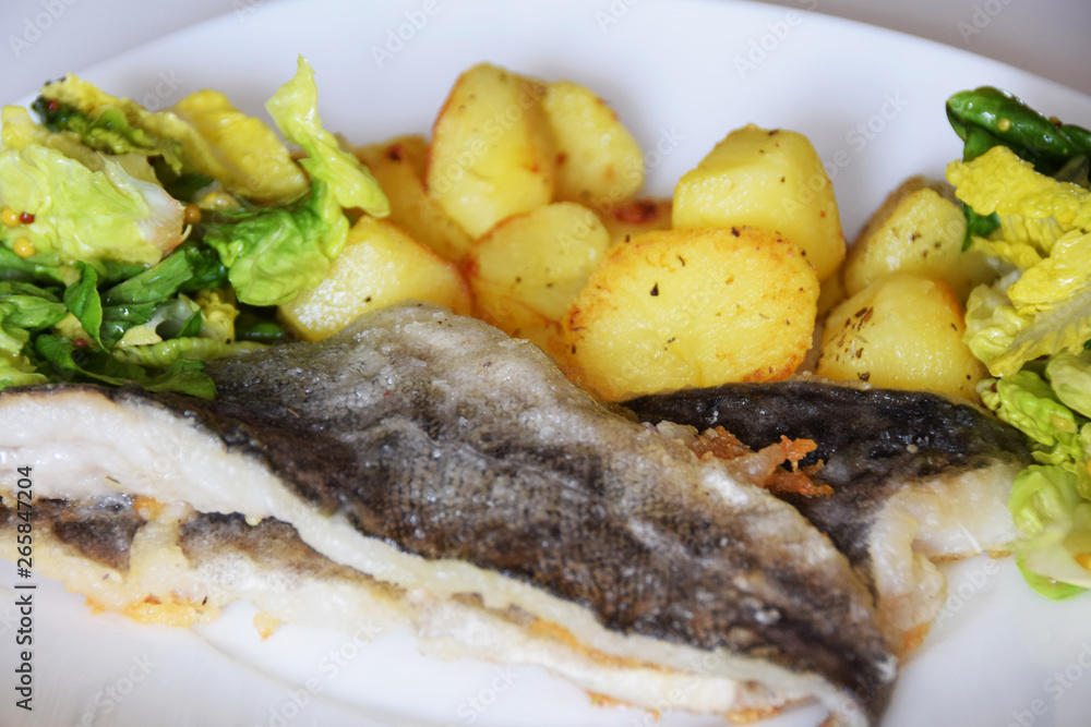 homemade dinner on a white plate baked potatoes fried fish cod, green lettuce with spices, homemade dinner on a white plate baked potatoes fried fish cod, green lettuce with spices,