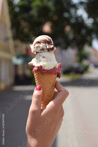 cold ice with three flavors of chocolate, vanilla and blueberry held in a woman's hand