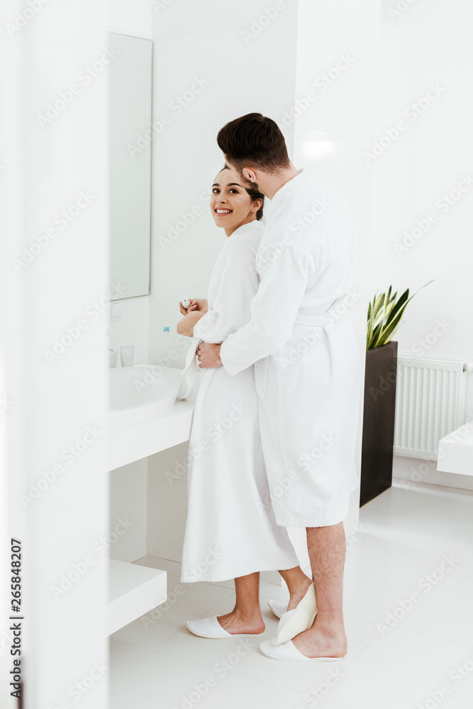 attractive woman looking at bearded boyfriend while standing in bathrobe in bathroom attractive woman looking at bearded boyfriend while standing in bathrobe in bathroom