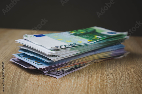 a large wad of cash bills dollar euro rubles in packs on a table of textured boards.