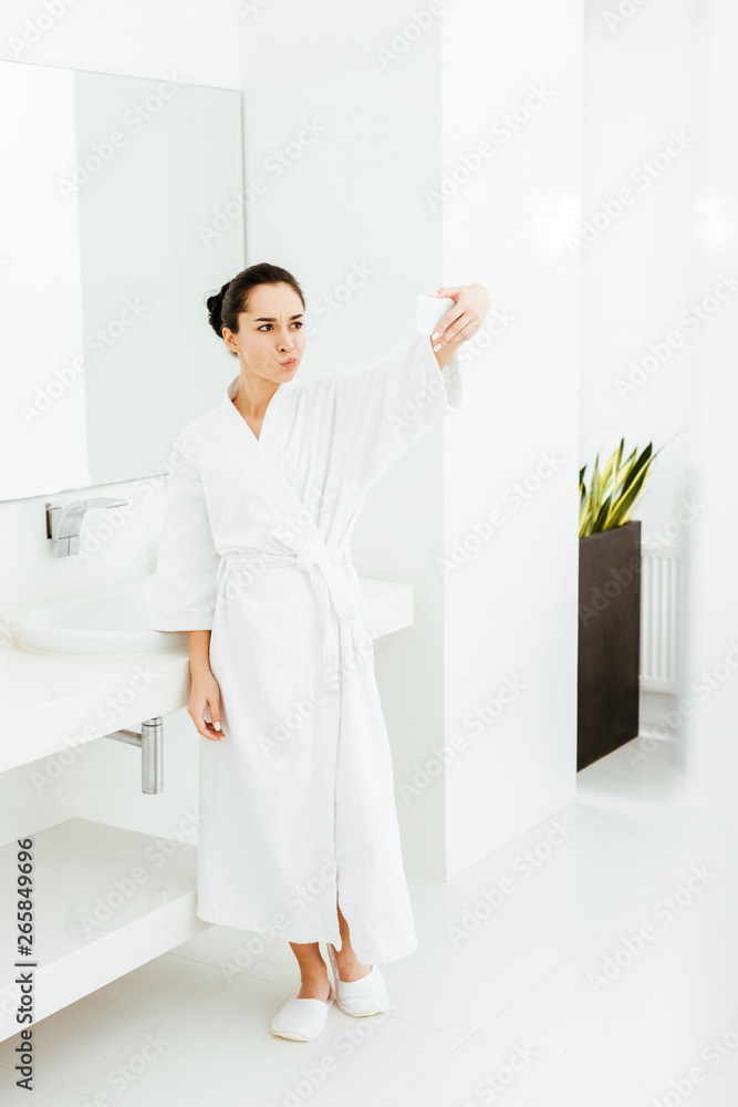 brunette young woman in white bathrobe taking selfie in bathroom brunette young woman in white bathrobe taking selfie in bathroom