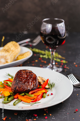 Fried pork with vegetables: green beans, carrots, paprika, garlic, greens, tomato and a glass of red wine,