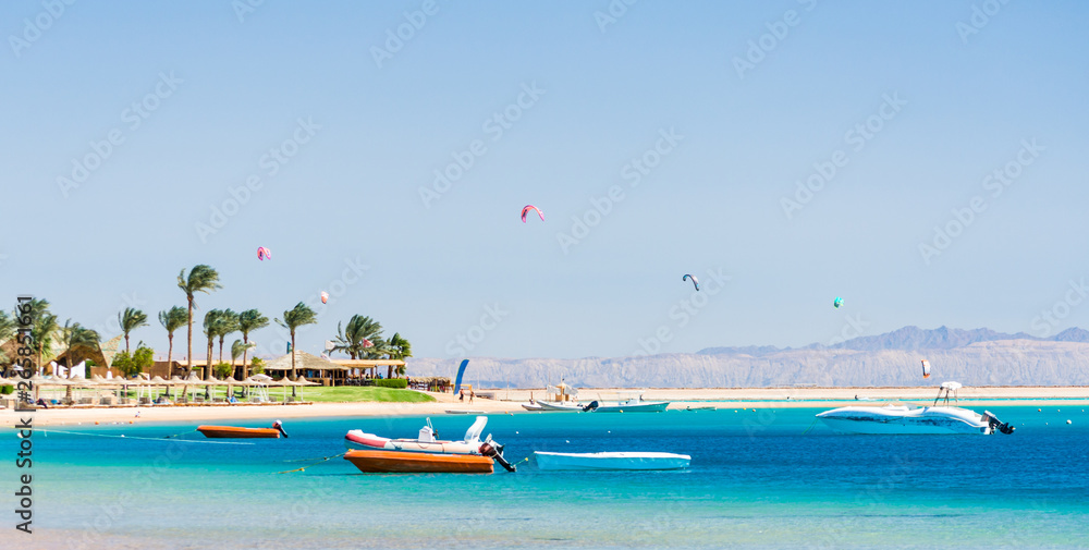 hotel with palm trees on the Red Sea in Egypt Dahab with boats and kite surfers
