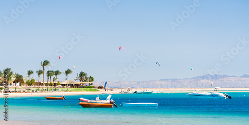 hotel with palm trees on the Red Sea in Egypt Dahab with boats and kite surfers photo
