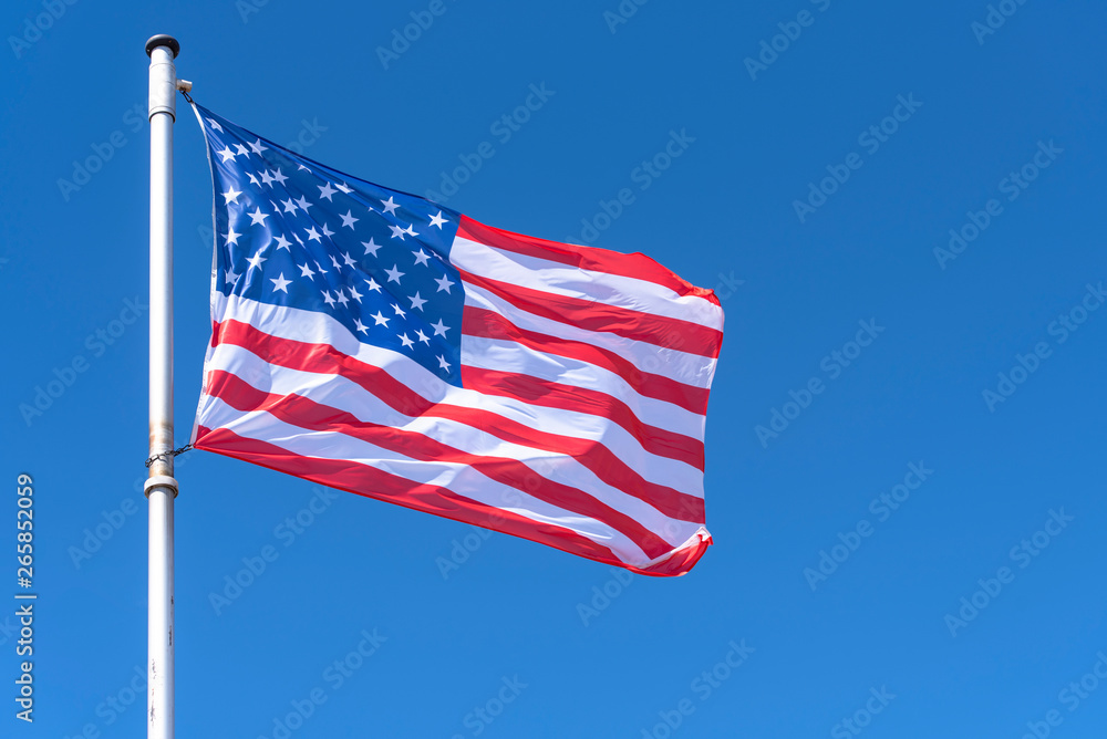 Fototapeta premium American Flag waving against blue Sky, USA Flag waving as Background