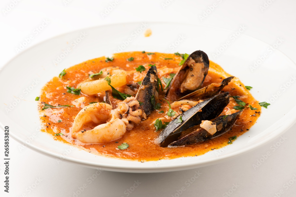Tomato soup with seafood and fish. Squids, scallops on a plate