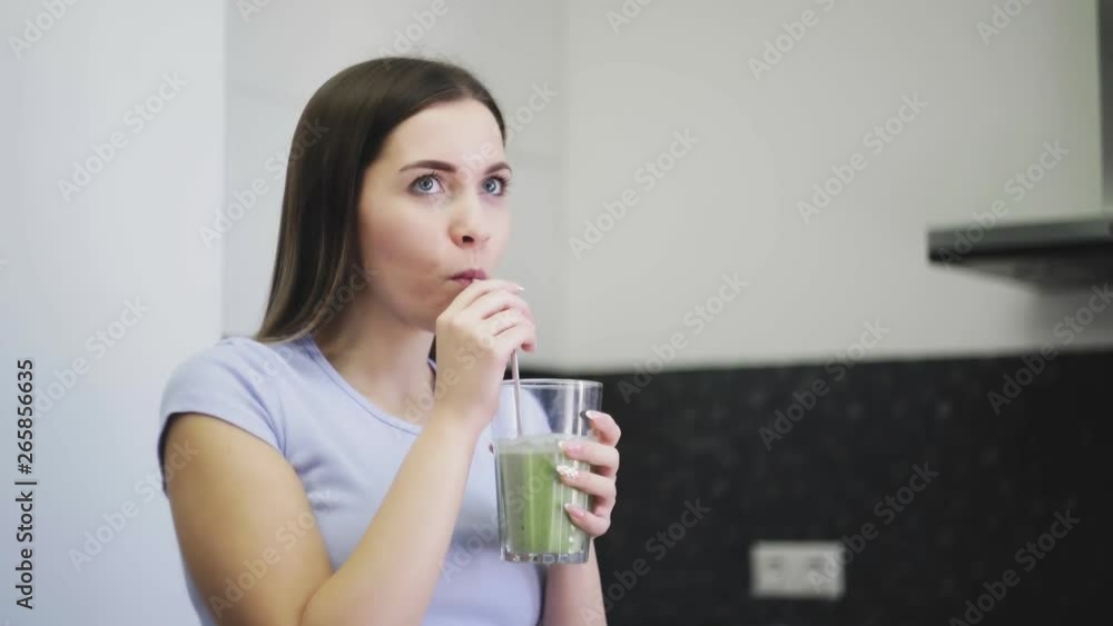 Woman is drinking smoothie from vegetables of fruits with milk through a straw Woman is drinking smoothie from vegetables of fruits with milk through a straw