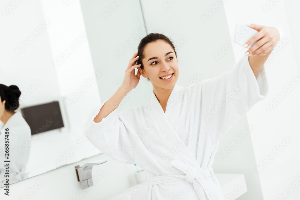 selective focus of happy young woman taking selfie in bathroom selective focus of happy young woman taking selfie in bathroom