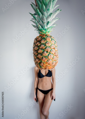 Female in bikini with pineapple on foreground.