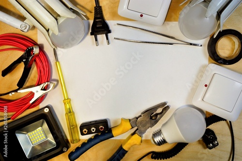 Electrician tool, frame of appliances for repair on white background. A set of tools for high-quality industrial repair of electrical wiring, lamps, floodlights, screwdriver, tape.