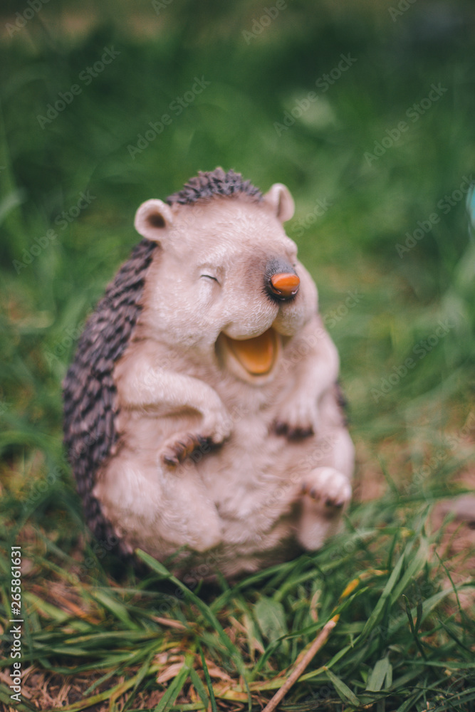 Close-up garden figurine funny hedgehog on green blurred background grass